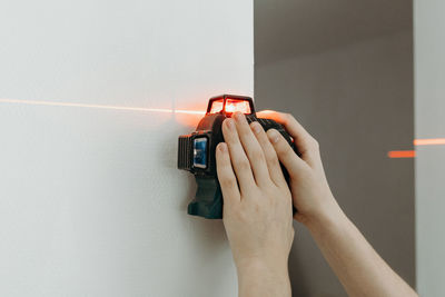 A young man uses a laser level on the wall.