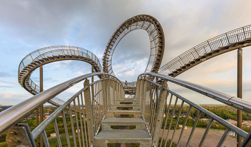 Low angle view of ferris wheel against cloudy sky