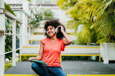 Smiling young man using mobile phone sitting outdoors