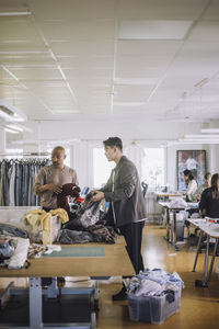 Male design professionals sorting recycled clothes at workshop