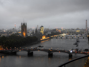 Illuminated city by river against sky over the thames river in london