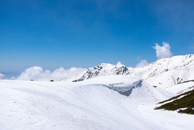 Scenic view of snowcapped mountains against blue sky