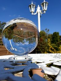 Close-up of crystal ball on glass against blue sky