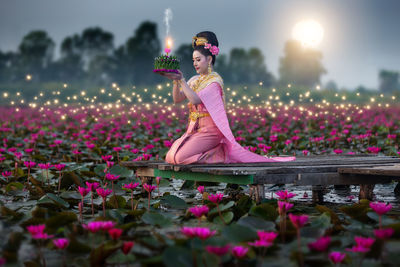 Woman standing by pink flowering plants