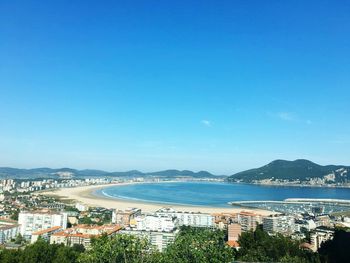 Scenic view of sea against clear blue sky in city on sunny day