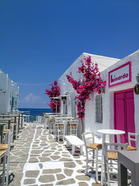 Empty chairs by building against clear blue sky