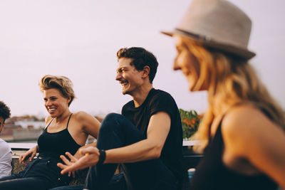 Cheerful friends having fun at rooftop party during dusk