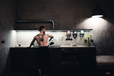 Rear view of man washing hands in bathroom