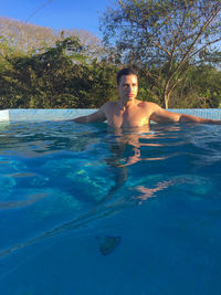 Shirtless young man relaxing in swimming pool