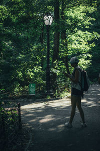 Full length of woman holding ball while standing by tree