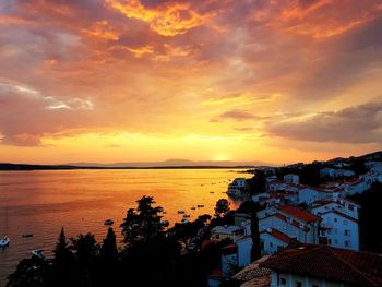 High angle view of buildings by sea against sky during sunset