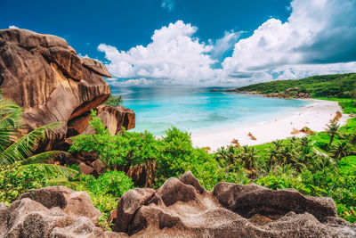 Scenic view of rocks by sea against sky