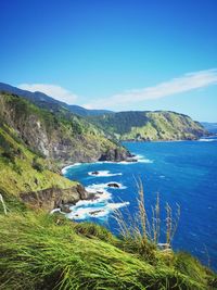 Scenic view of sea and mountains against blue sky