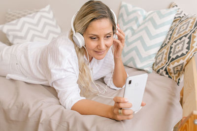 Midsection of woman using mobile phone on bed