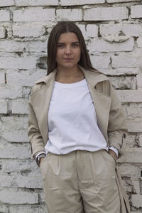 Portrait of a smiling young woman standing against brick wall