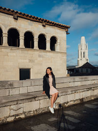 Full length of woman sitting on pier against sky