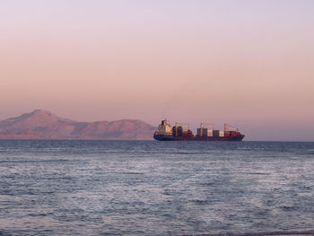 Ship sailing on sea against sky during sunset