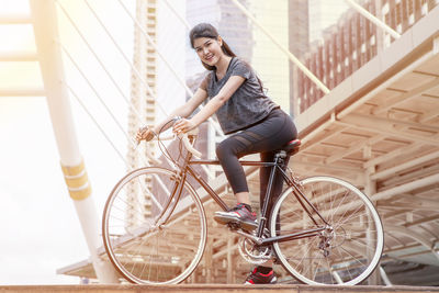 Young woman riding bicycle on railing