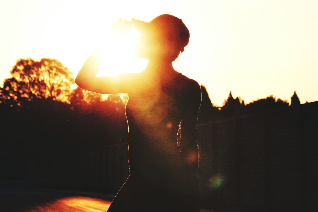 SILHOUETTE WOMAN STANDING AGAINST SKY AT SUNSET