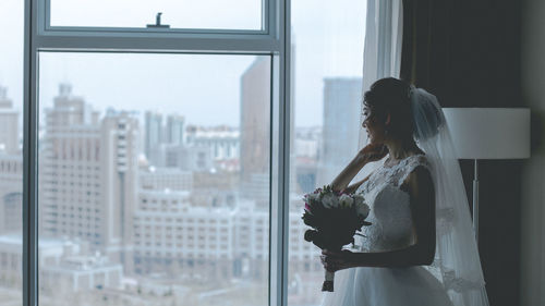 Young woman looking through window