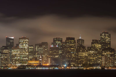 Illuminated buildings in city against sky at night