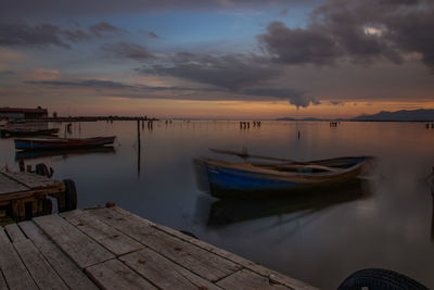 Boats moored in sea against sky during sunset