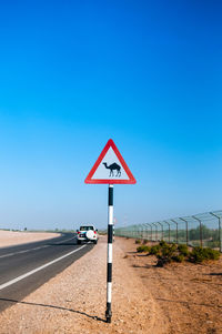 Road sign against clear blue sky