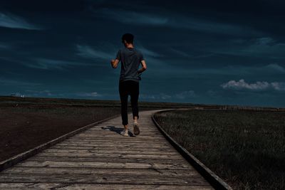 Full length rear view of man walking on footpath