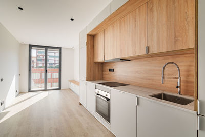 Contemporary minimal kitchen and living room with balcony at empty refurbished apartment. 