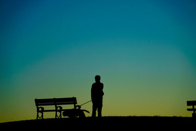 Silhouette woman walking on field against clear sky during sunset