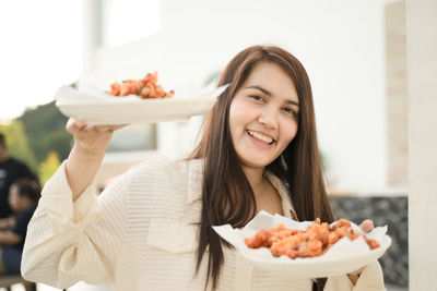 Portrait of young woman having food at home