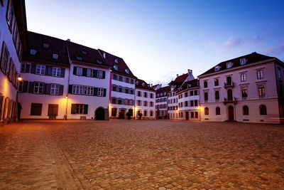 Houses by street against sky in city at dusk