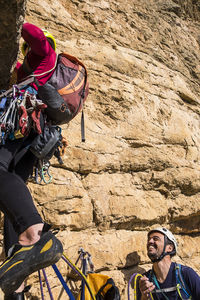 Hikers climbing rock formation on sunny day