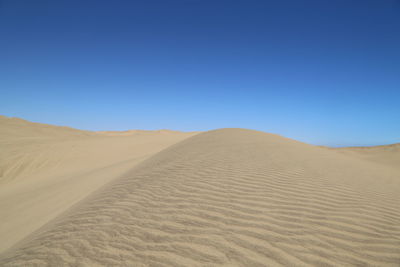 Scenic view of desert against clear blue sky