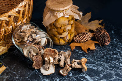 High angle view of mushrooms in jars by pine cones on table