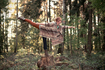 Woman standing on tree stump in forest