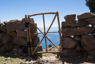 Rusty metallic structure on shore against clear sky