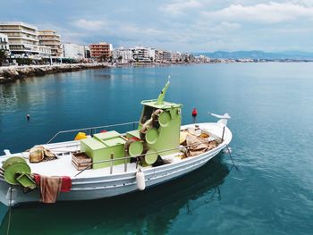 Boats moored in sea against buildings in city