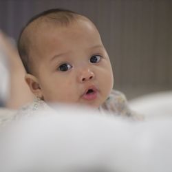 Close-up of cute baby boy lying on bed at home