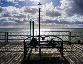 Woman sitting on pier over sea against sky