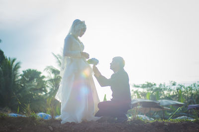 Side view of couple on field against sky