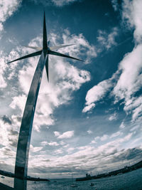 Windmills on landscape against cloudy sky