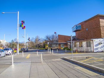 Road by buildings against clear blue sky