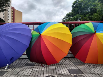 Multi colored umbrellas on footpath against sky in city