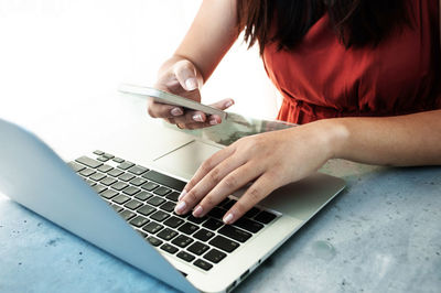 Midsection of woman using mobile phone on table