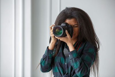 A beautiful african-american photographer girl with a camera. photo shoot in the studio.