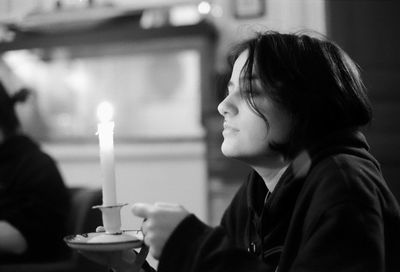 Close-up of woman holding candle sitting at home