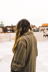 Rear view of young woman against built structure in winter