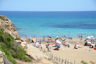 Group of people on beach against clear sky