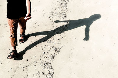 Low section of man walking on sand